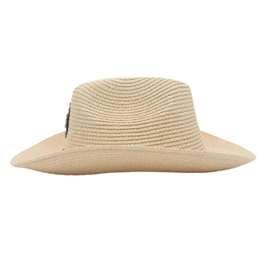 Détail d'un chapeau de cowboy en paille avec badge métallique noir et texture tressée fine