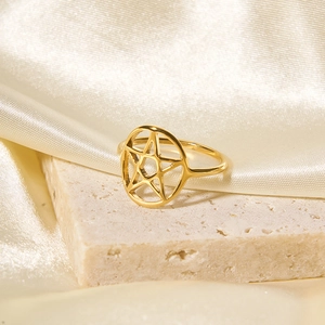 Nahaufnahme eines goldenen Edelstahl-Sternrings auf strukturiertem Stein und Seide