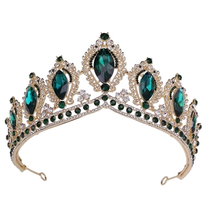 Macro view of golden baroque crown with emerald green stones and diamond accents