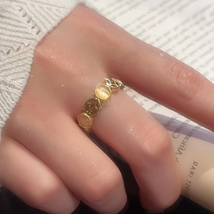 Macro view of gold ring featuring cat-eye stones and openwork ancient coin patterns