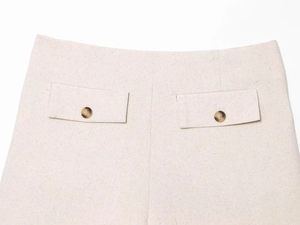 Dettaglio dei pantaloncini in lino con tasche posteriori e bottoni effetto tartaruga