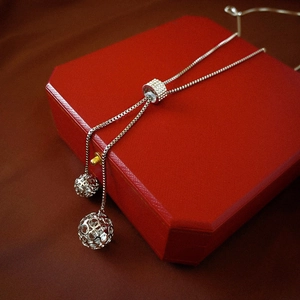 Detail of silver stainless steel long necklace with hollow ball pendants and pavé slider