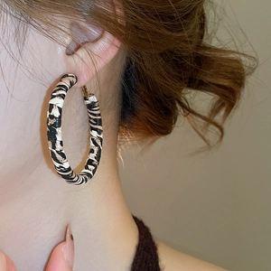 Gros plan de boucles d'oreilles créoles zébrées portées par un mannequin de profil