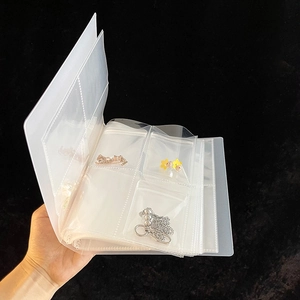 Handheld view of a transparent PVC jewelry storage book with anti-oxidation pouches