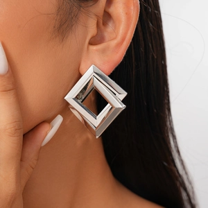 Close-up of geometric diamond-shaped silver earrings worn on model for a minimalist look