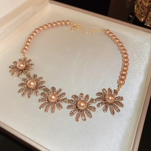 Macro shot of peach pearl flower necklace with crystals in a beige jewelry gift box