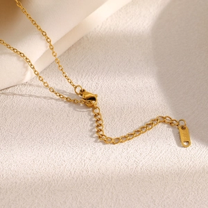Détail macro d'une chaîne en acier doré 18K avec étiquette gravée K18 et un fermoir