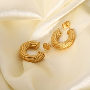 Detailed view of 18K gold plated stainless steel twisted hoop earrings on silk fabric