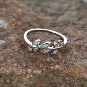 Silver olive branch ring with white opal stones and zircons on a natural rock surface