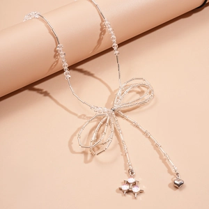 Detail of silver beaded necklace with bow design, heart pendant and pink crystal charms