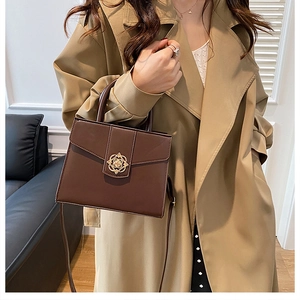 Détail d'un sac à main marron foncé avec fermoir fleur doré et texture en cuir PU