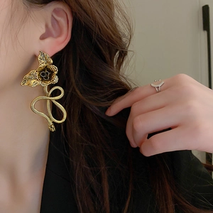 Close-up of vintage gold flower and snake earrings worn by a model for a stylish look