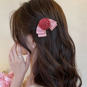 Elegant hair clip with red satin rose and pink bow design worn on model's hair