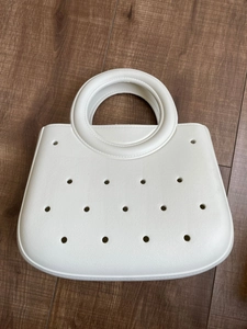 Détail du sac de plage en EVA blanc avec poignées rondes sur fond de parquet en bois