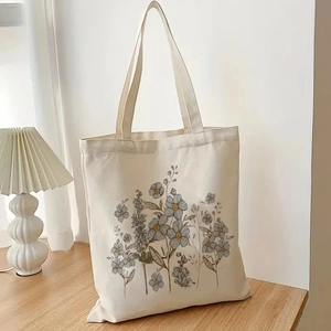 Aesthetic beige canvas tote bag with soft blue floral prints on a wooden table