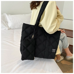Detail of black quilted puffer tote bag with matching coin pouch on a yellow blazer