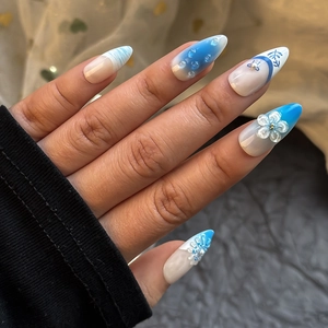 Macro detail of 3D shell and pearl accents on blue gradient stiletto press-on nails