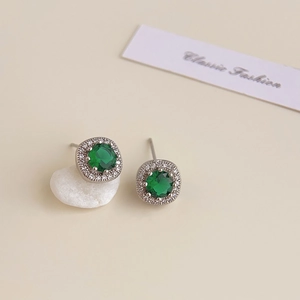 Close-up of 18K silver-plated halo stud earrings with green emerald and white crystals