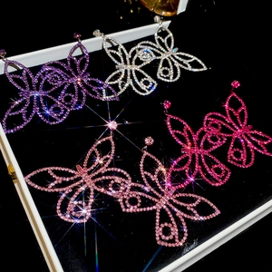 Detailed close-up of butterfly earrings with colorful zircons in a black jewelry box