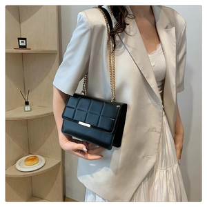 Detail of black quilted crossbody bag featuring gold chain strap and metal trim on flap
