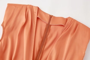 Détail de la fermeture éclair invisible et de l'encolure sur la robe en satin orange