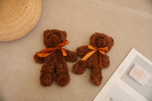 Close-up of small dark brown teddy bear plush toys with bright orange satin bows