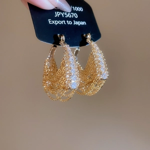 Macro detail of 18k gold plated drop earrings with zircon stones and layered chains