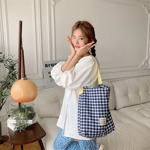 Détail du sac cabas en toile à carreaux bleus et blancs avec bandoulière jaune sur modèle