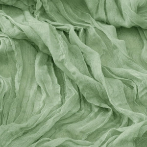 Macro shot of light green crinkled cheesecloth fabric texture with soft gauze weave