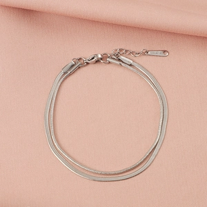 Detail view of double-layer stainless steel snake chain bracelet on pink fabric