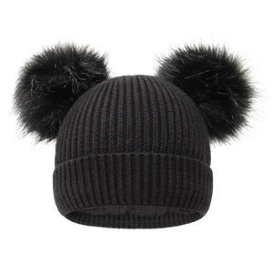 Detail showing the thick vertical knit texture and soft faux fur pom-poms on the winter beanie