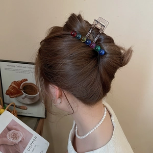 Close-up of a brown acrylic hair claw clip with colorful beads worn on a twisted hairstyle