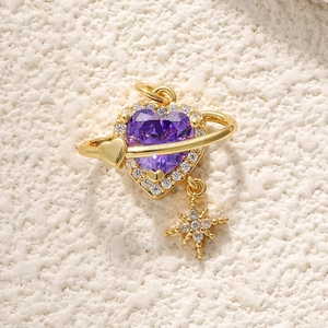 Detail of 18K gold heart pendant with purple gemstone, planet ring, and star charm