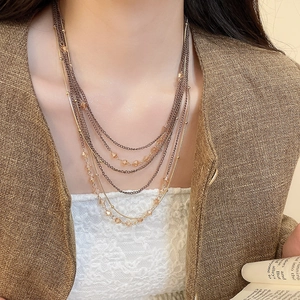 Detail of multi-layer beaded necklace with amber crystal charms and gold beads on a model