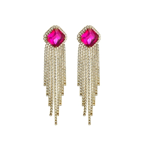 Detailed close-up of luxury long tassel earrings with rose red crystal and gold fringe