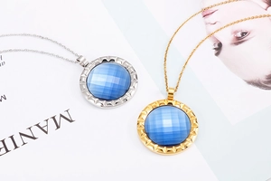 Detail of gold and silver necklaces with faceted blue crystal stone in gear frame