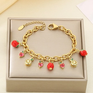 Detailed view of golden charm bracelet with strawberry, heart, and lemon pendants