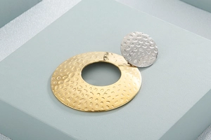 Detailed studio shot of geometric hammered metal earring in gold and silver finish