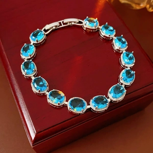 Detail of oval blue zircon link bracelet with diamond border on luxury red wood case