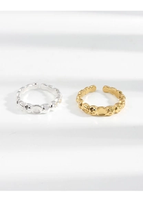 Dettaglio di anelli aperti in oro e argento con trama martellata irregolare su bianco