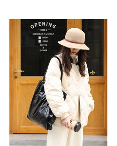 Outdoor street style view of a black glossy nylon tote bag paired with a puffer jacket