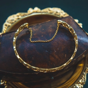 Detailed close-up of a vintage golden bangle featuring an intricate safety chain design