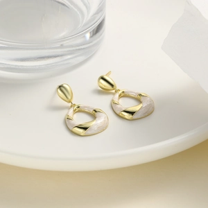 Detail shot of vintage gold-tone oval earrings with white marble resin on a ceramic tray