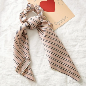 Detail of satin ponytail holder with navy and yellow stripes on a soft beige base