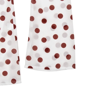 Detailed close-up of white chiffon fabric with red polka dots on a flared hemline