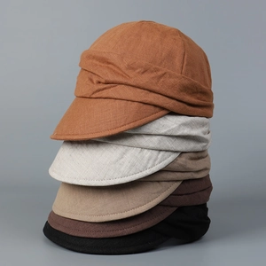 Vertical stack of breathable linen newsboy hats showing textured pleats and five earth tones