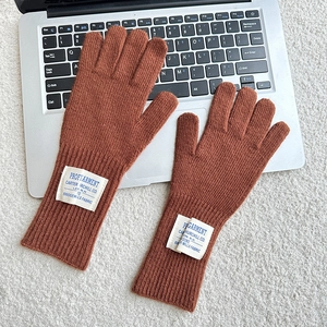 Detail of brown knitted gloves with vintage label on a laptop keyboard background