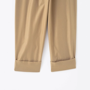 Close-up of khaki pleated trousers showing the cuffed hem detail in twill fabric texture