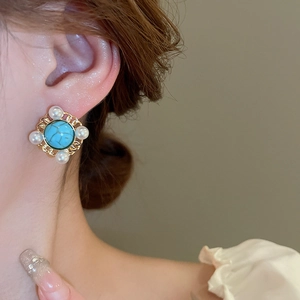 Detailed close-up of a French vintage turquoise earring with pearls on a model ear