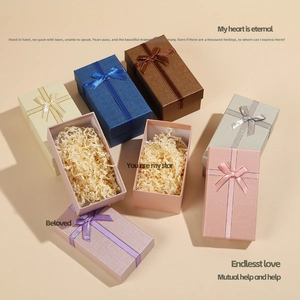 Rectangular gift box with elegant ribbon bow and shredded paper filler for jewelry storage